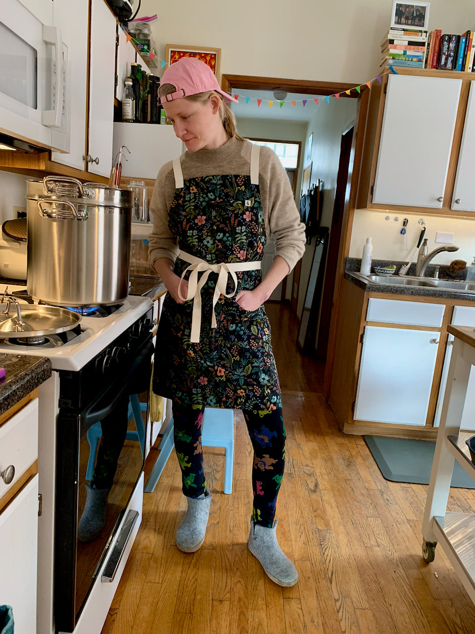 Lili wearing a floral apron in a kitchen